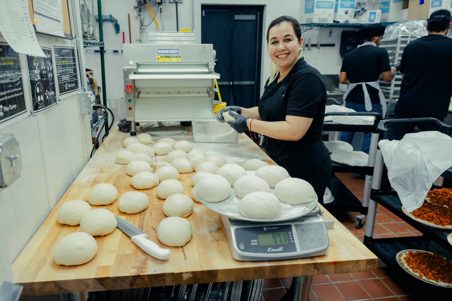 A fellow Curry Pizza staff rolling out fresh dough for pizza crust's