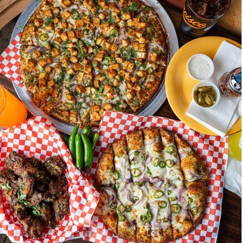 Clickable image showing two pizzas with chicken and jalapeños, plus spicy wings and sauces. Should open an Instagram external link to the source image.